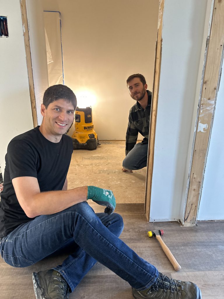 Two volunteers smiling on the floor inside of the home they are helping build